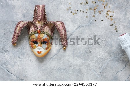  Carnival mask, white champagne bottle and gold glitter confetti. Top view, Close up on marble background.