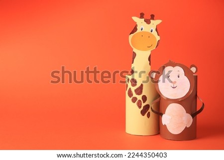 Toy monkey and giraffe made from toilet paper hubs on orange background, space for text. Children's handmade ideas