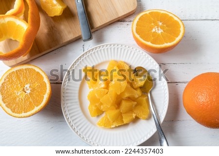 Chopped and peeled oranges on a plate for healthy snack or dessert. Served on white wooden background. Flat lay