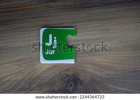 Jigsaw puzzle piece with jar lettering and letter j placed on wooden background