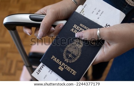 Young girl showing the Argentine passport with her travel bags. Translation: "Pasaporte" mean Passport. "Mercosur: República Argentina" mean Mercosur Argentina Republic.