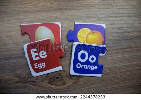 Puzzle pieces with pictures of eggs, oranges and inscriptions of eggs, oranges placed on wooden background