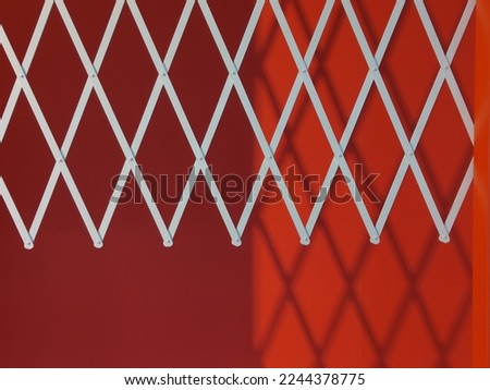 reflection of white bars on a red wall. geometric shadows on the wall.
