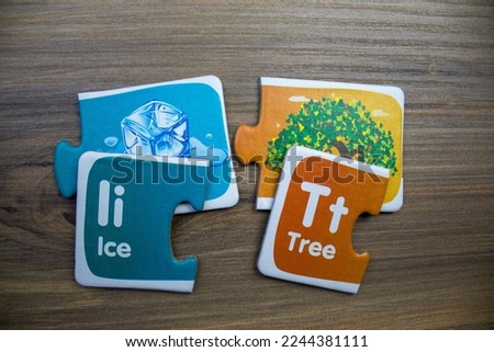 Puzzle pieces with pictures of tree, block ice and words tree, block ice, placed on wooden background