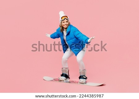 Side view snowboarder sportive fun woman wear blue suit goggles mask hat ski padded jacket snowboarding isolated on plain pastel pink background. Winter extreme sport hobby weekend trip relax concept Royalty-Free Stock Photo #2244385987
