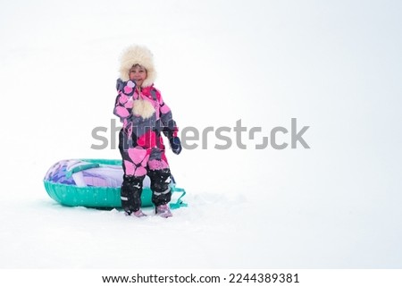 Downhill skiing. A happy child with a frosty blush on his face with an inflatable sled on a background of snow. Copy space.                               