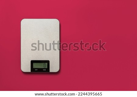 Digital kitchen scales against viva magenta background. Electronic scales for food weight measurement. Design element for dieting and cooking. Color of the year 2023. Copy space. Top view. Royalty-Free Stock Photo #2244395665