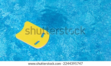 Safe pool training aid float foam board tool. Yellow Swimming kickboard on blue water surface of swim pool. Mockup, Panoramic banner, copy space for text or design. Water sport, active lifestyle