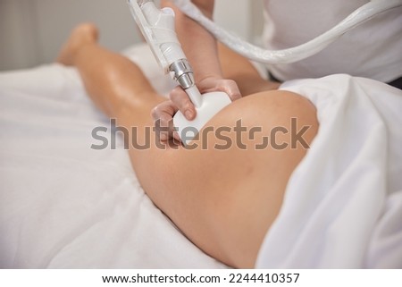 vacuum-roller manipulator, massage salon, body correction. Young woman in beauty salon doing beauty services, body shaping. Masseur is making vacuum roller massage for client, figure correction