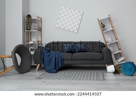 Interior of messy living room with shelf units and sofa near light wall Royalty-Free Stock Photo #2244414507