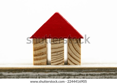 Miniature house formed with wooden dowels on a white background