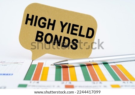Business concept. On the financial charts lies a pen and a sign with the inscription - high yield bonds