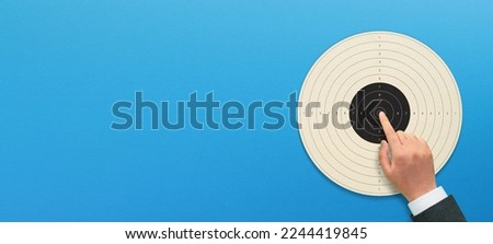 Target business concept with hand on blue background