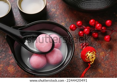 Spoon and bowl of tangyuan with Chinese decor on grunge background, closeup. Dongzhi Festival