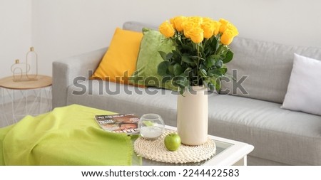 Vase with beautiful yellow roses on table in living room