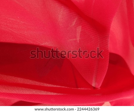 Wavy red chiffon fabric with a maple leaf silhouette showing through the folds (macro, texture).