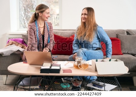 Women communicate while sitting in front of laptop on sofa