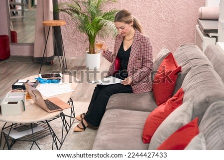 Stylish lady reads documents while sitting on a sofa