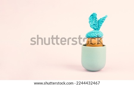 Cute easter bunny or rabbit with a smiling egg face in a cup, spring holiday, greeting card 