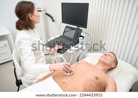 Doctor carefully looks at the screen of the ultrasound machine Royalty-Free Stock Photo #2244433953