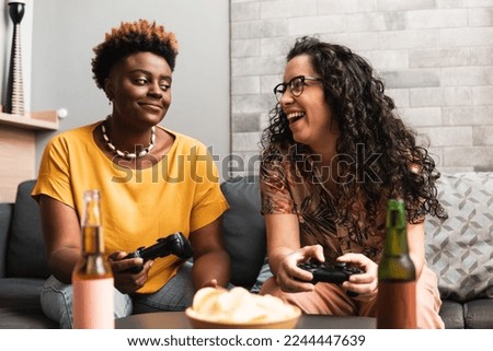 Partner plays with the other and they play video games on the sofa in the living room at home Royalty-Free Stock Photo #2244447639