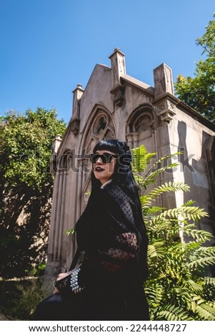 Stylish dark gothic girl in large ancient abandoned mausoleum with neoclassical style with blue sky in a sunny day