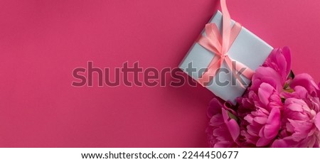 Valentine's Day Background with Pink Peonies and Gift Box With Satin Pink Bow on a Viva Magenta Color Background.