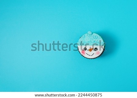 Snowman cupcake  with copyspace on blue background. Christmas concept.