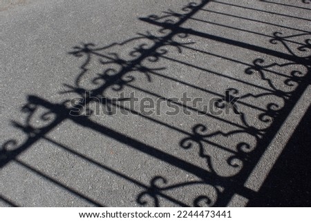 Metal house fence dark shadow on grey city street asphalt road