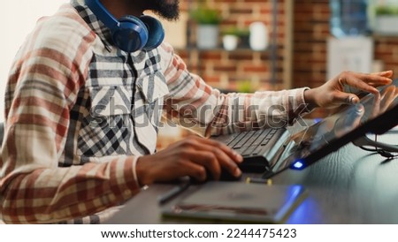 Post production house employee editing photos on touchscreen display, using tablet and stylus pen in office. Male photographer creating multimedia content with retouching software.