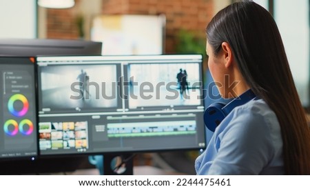 Young content creator editing video and audio montage on computers, creaating movie with professional studio footage. Female videographer using color grading to edit clips in post production agency.