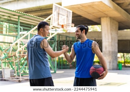Two man basketball players shaking hand after playing one on one streetball match on outdoors court under highway in the city. Fair game competition, sportsmanship and outdoor sport training concept. Royalty-Free Stock Photo #2244475941