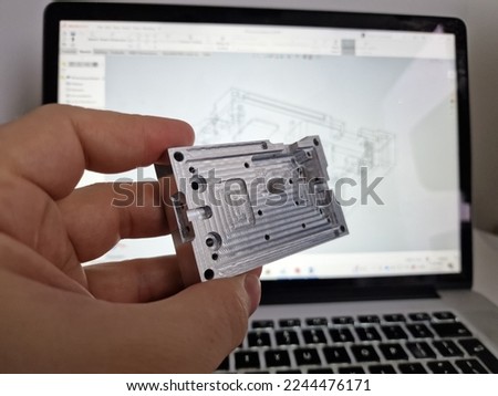 Mechanical engineer hand holding CNC milled custom designed project in front of computer screen and drawings Royalty-Free Stock Photo #2244476171