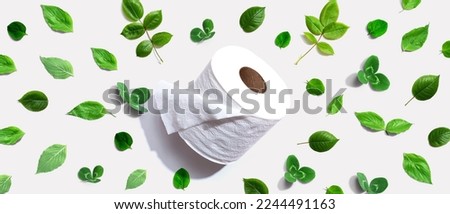 A roll of toilet paper with green leaves - flat lay Royalty-Free Stock Photo #2244491163