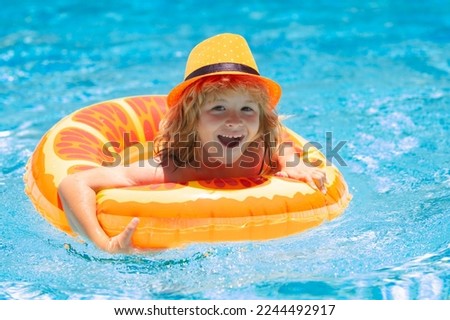 Child in pool in summer day. Children playing in swimming pool. Kids holidays and vacation concept.