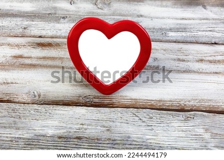 Red heart pattern picture frame standing up on a white wood desk background for a happy Valentines day concept 