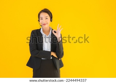 Portrait beautiful young business asian woman with headphone or headset for call center or telemarketing on yellow isolated background
