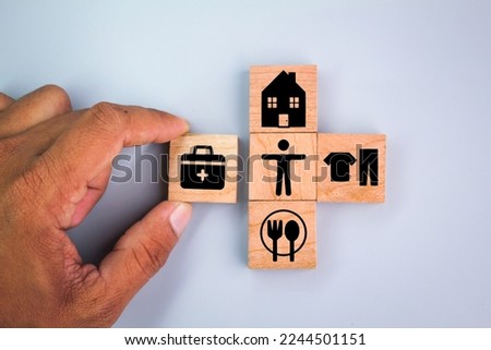 wooden cube with icons of food, Clothing, housing, medical bag, four basic human needs concepts. The Four Basic Material Needs of the Human Being. Royalty-Free Stock Photo #2244501151