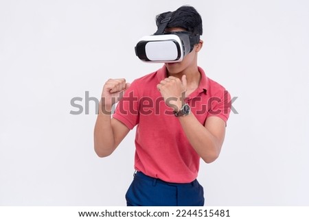 A young asian man playing a VR boxing or other fighting game via a virtual reality headset. Isolated on a white backdrop.