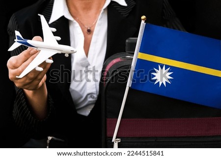 business woman holds toy plane travel bag and flag of Nauru 