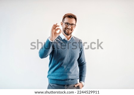 Portrait of a successful businessman gesturing okay sign and smiling at the camera.