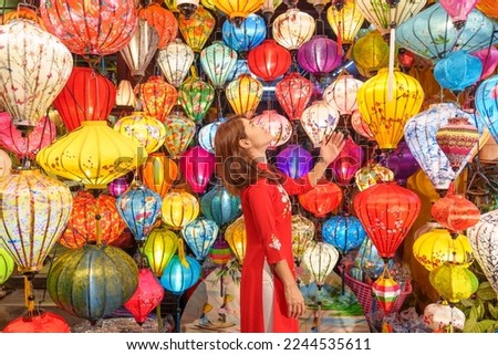happy woman wearing Ao Dai Vietnamese dress with colorful lanterns, traveler sightseeing at Hoi An ancient town in central Vietnam.landmark for tourist attractions.Vietnam and Southeast travel concept Royalty-Free Stock Photo #2244535611