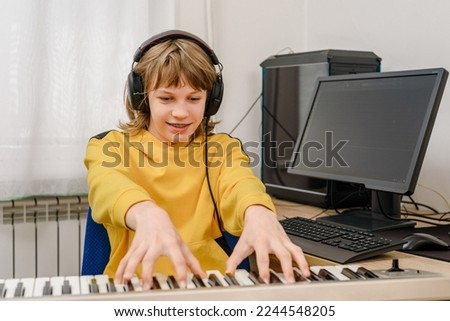Happy teenager boy learning to play piano music at home studio Royalty-Free Stock Photo #2244548205