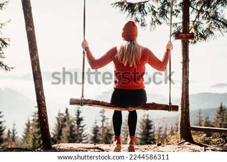 Woman swinging on swing in sunny winter dayin the ferest. Wooden swing with swinging free, happy woman outdoors. Healthy lifestyle vacation. Zazriva, slovakia