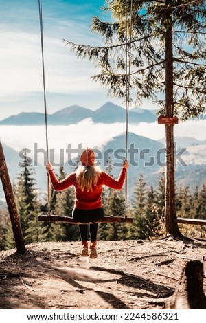 Woman swinging on swing in sunny winter dayin the ferest. Wooden swing with swinging free, happy woman outdoors. Healthy lifestyle vacation. Zazriva, slovakia