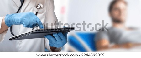 Doctor in medical office reviewing the data on his tablet with a patient in the background. Physician with sick person analyzing data of medical report in digital tablet on medical room background Royalty-Free Stock Photo #2244599039