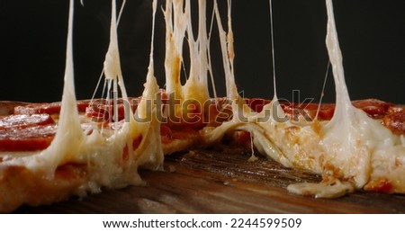 Close up shot of taking a piece of freshly baked pizza with tasty stretchy cheese. Delicious Italian pizza from the oven on black background. food and drink  Royalty-Free Stock Photo #2244599509