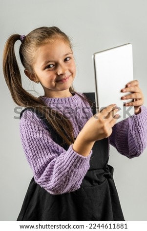 cute little girl holding tablet smiling isolated on plain background. little girl concept. selfie portrait of a child