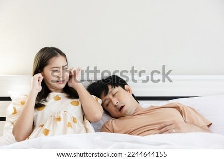 Asian couple lying on the bed Men have a problem with loud snoring that annoys women. Causes of sleep apnea stroke chronic depression Abnormal body stress. copy space Royalty-Free Stock Photo #2244644155