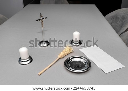 A steel caroling set lying on a gray tablecloth, traditional priest caroling in Poland, with an envelope with money.